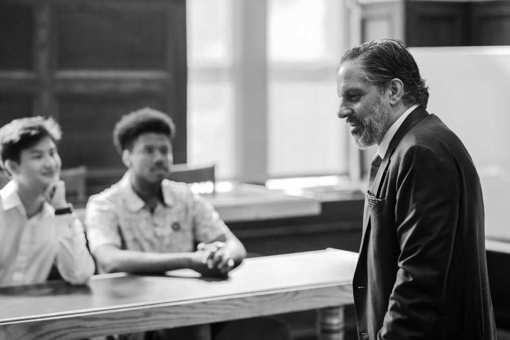 A black-and-white image of Georgetown's president speaking with students in a classroom
