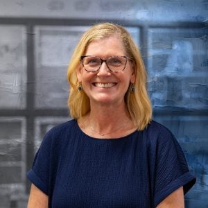 A blonde-haired woman with glasses smiles