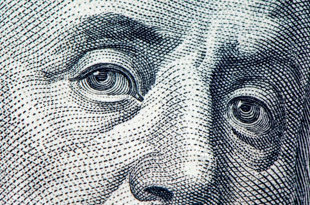 A close-up of Benjamin Franklin's eyes from the dollar bill
