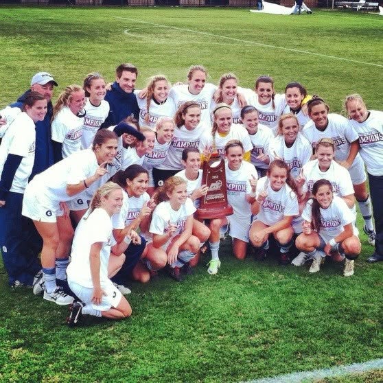 Female soccer team holding up a trophy