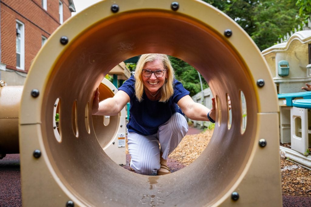A woman looks through a toy tunnel on a playground
