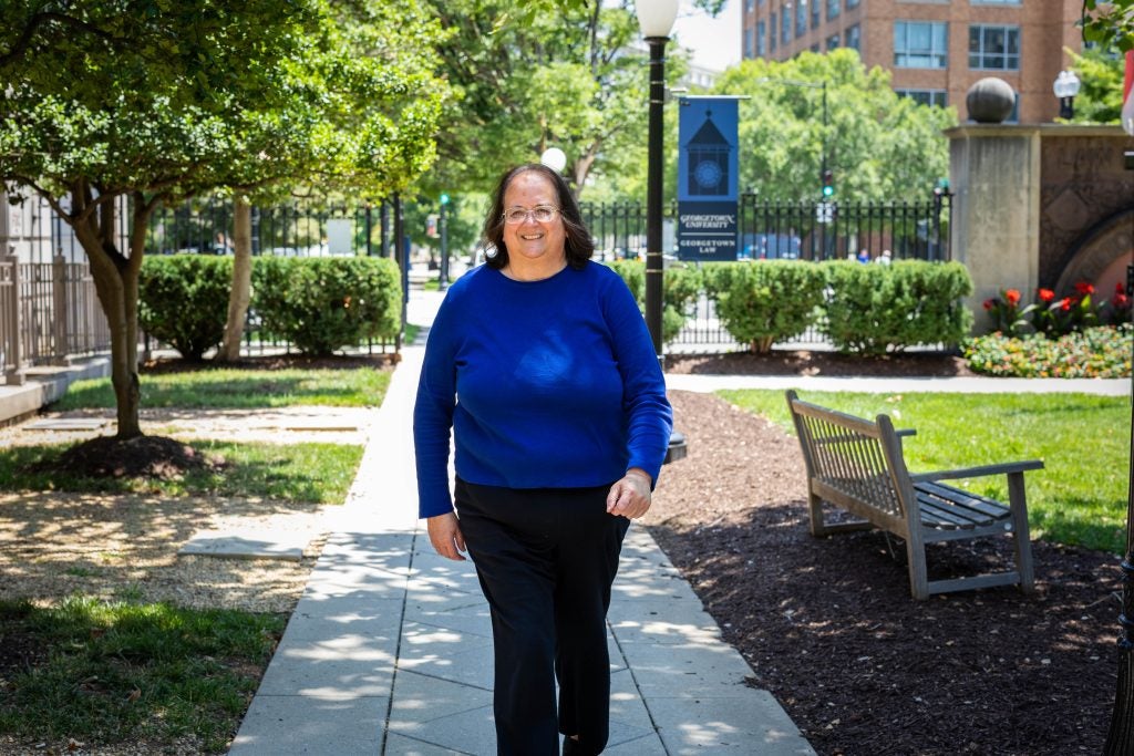 A woman in a bright blue shirt walks on Georgetown Law's campus