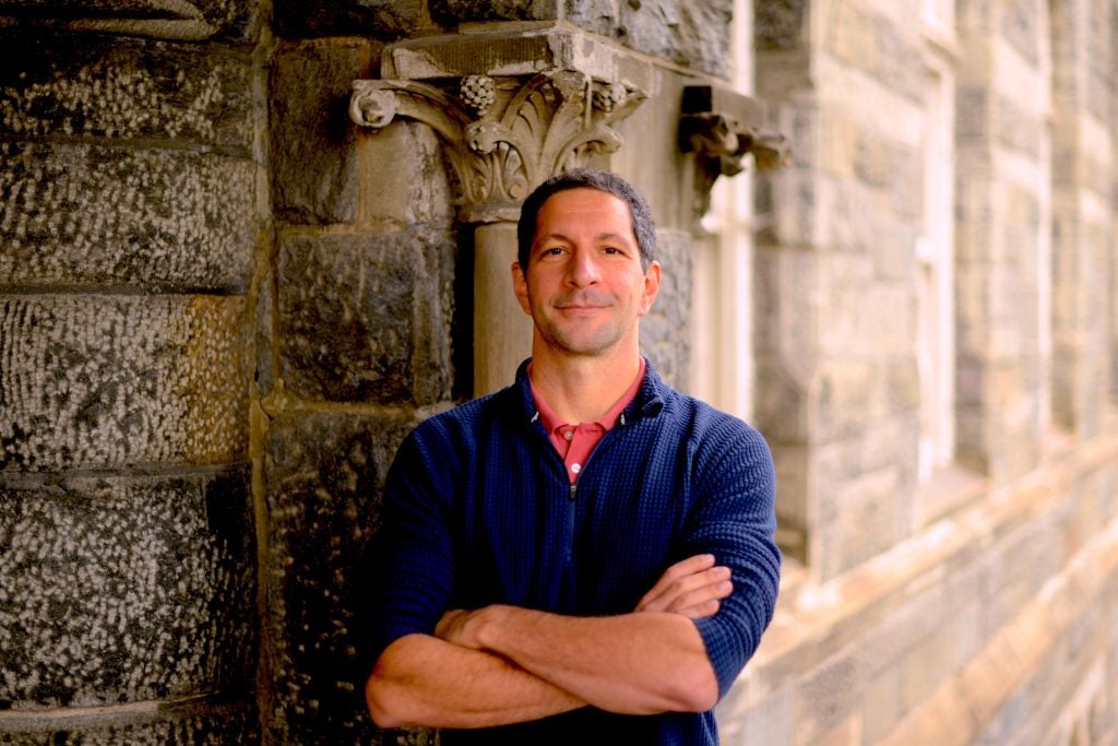 Man with arms crossed while wearing a blue quarter zip and smiling