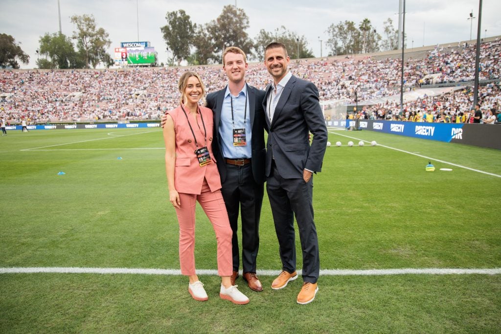Young women with two young men in business attire on a soccer field