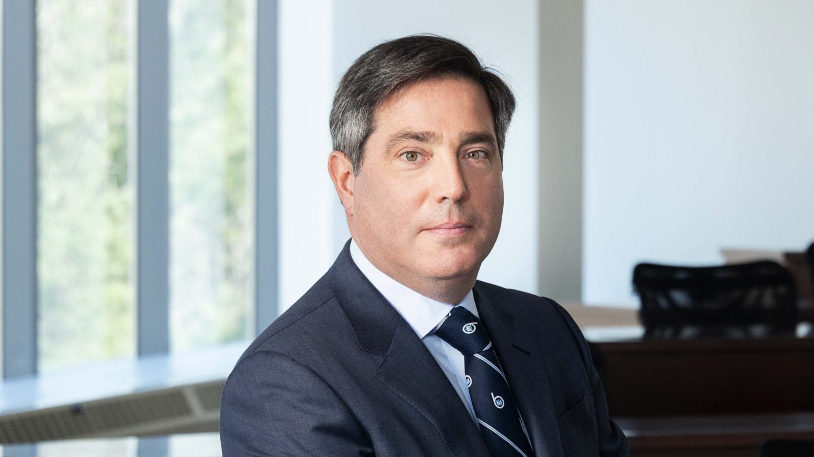 A headshot of a man in a navy blue suit