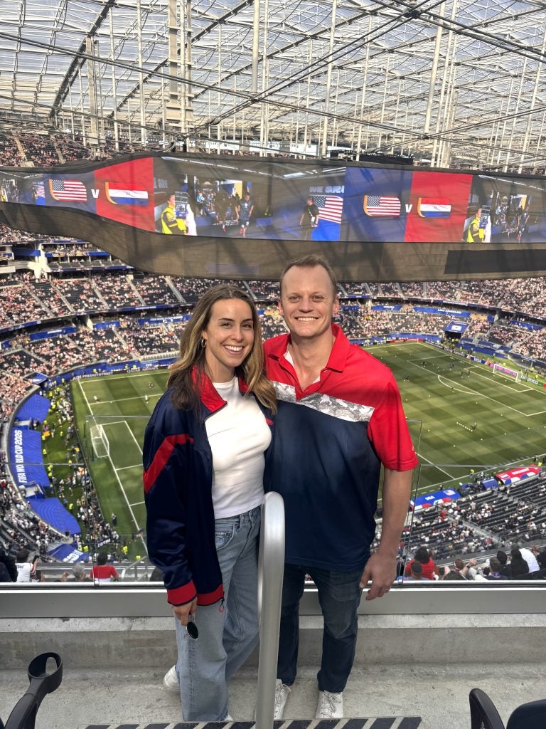 A young man and woman at a soccer match in an indoor stadium