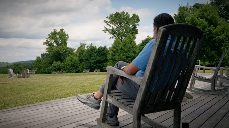 Georgetown President Eduardo Peñalver sits on a rocking chair overlooking a field