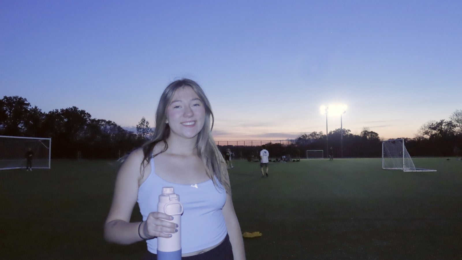 Young woman in athletic clothes on a soccer field in the evening