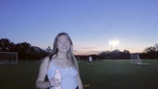Young woman in athletic clothes on a soccer field in the evening