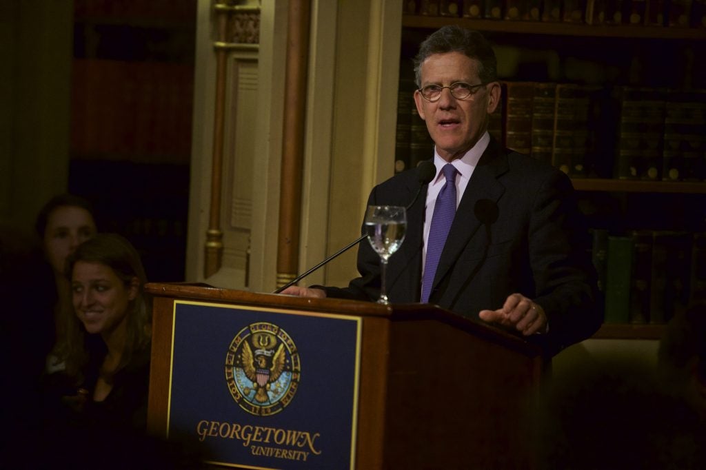 Tim Brosnan in suit and tie speaking at a podium