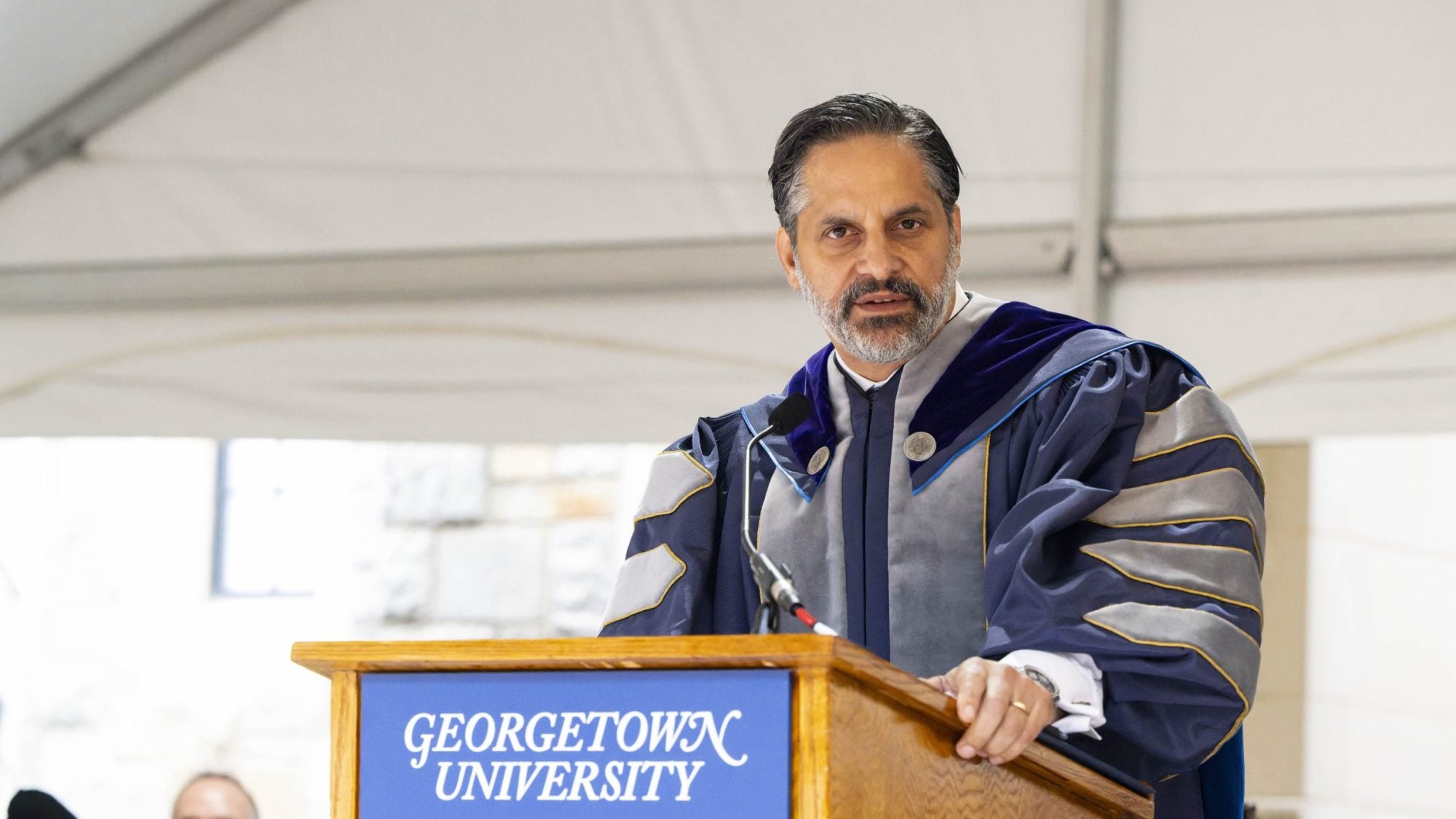 Eduardo Peñalver in academic regalia speaking at the podium