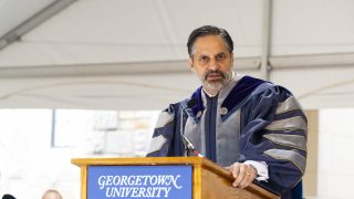 Eduardo Peñalver in academic regalia speaking at the podium