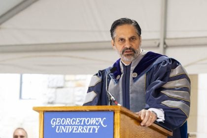 Eduardo Peñalver in academic regalia speaking at the podium