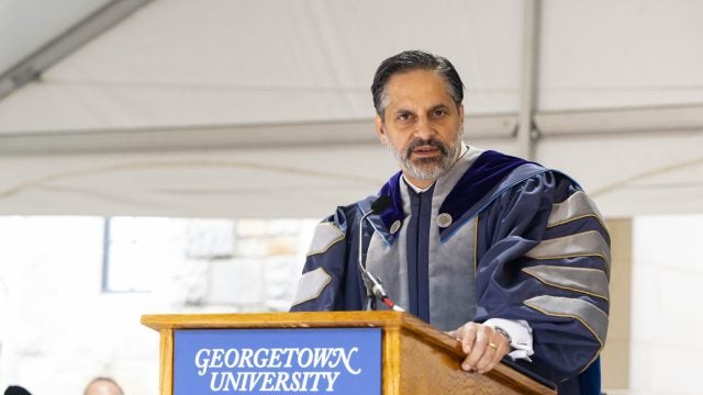 Eduardo Peñalver in academic regalia speaking at the podium
