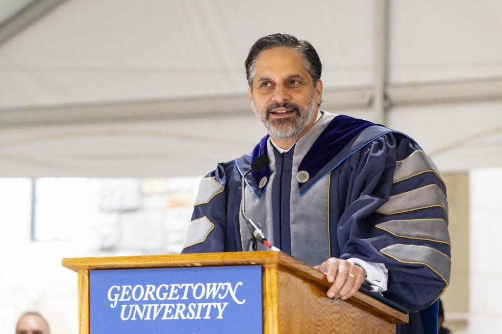 Eduardo Peñalver in academic regalia speaking at the podium