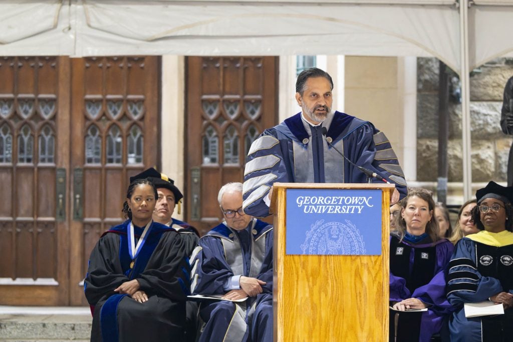 Eduardo Peñalver in academic regalia speaking at the podium