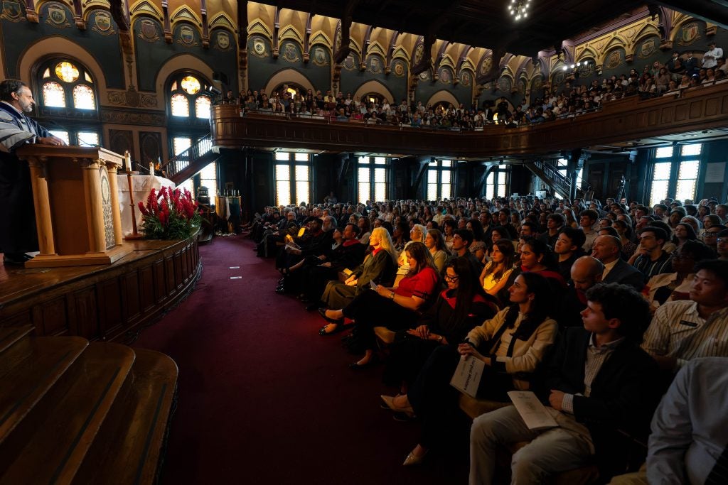 Peñalver delivering remarks at the podium in Gaston Hall to a packed room