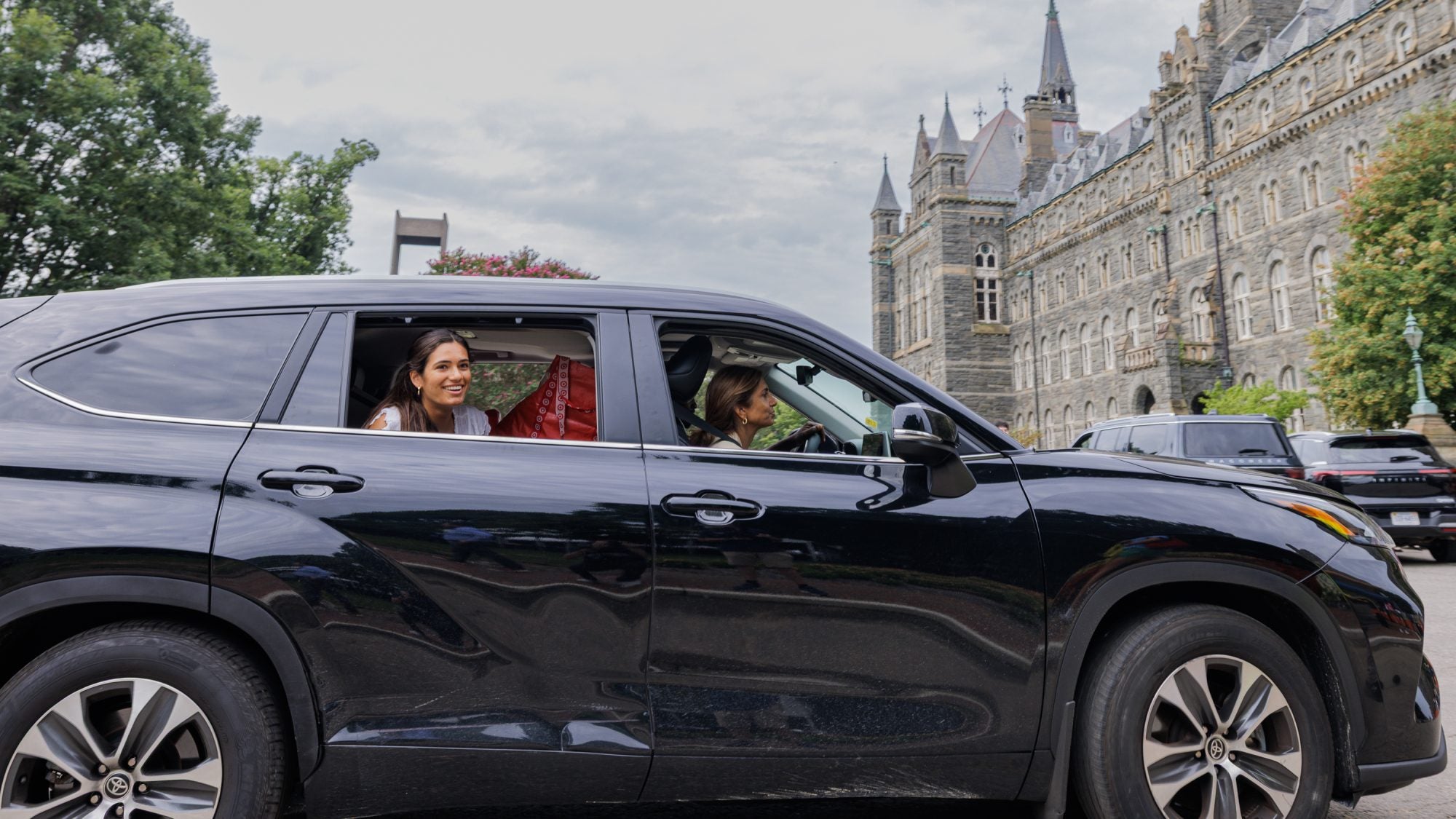 Black SUV with young woman smiling as she arrives at GU