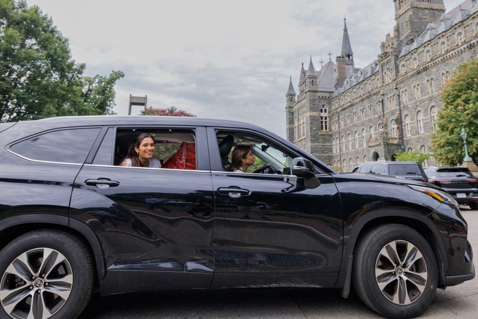 Black SUV with young woman smiling as she arrives at GU
