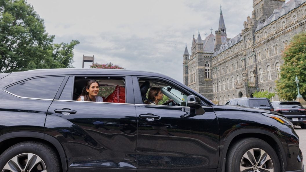 Black SUV with young woman smiling as she arrives at GU