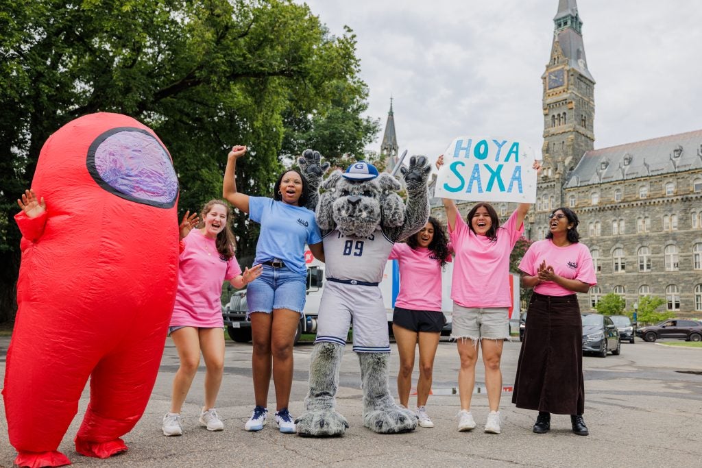 Students in costumes and pink shirts excited in front of Healy Hall