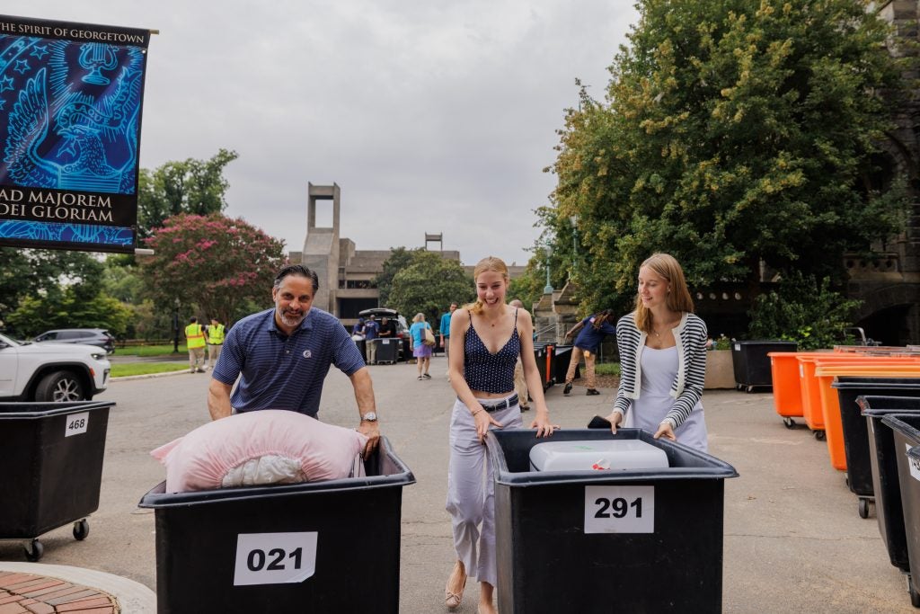 Eduardo Penalver and two students move two moving bins