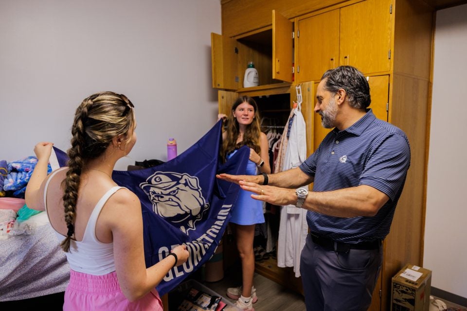 Two young women show their GU flag to Eduardo Peñalver