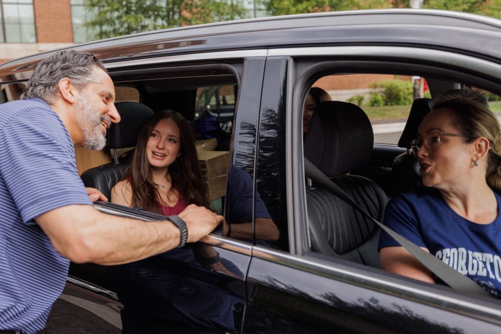 Eduardo Peñalver talks to a student and her mom as they pull up in a black car