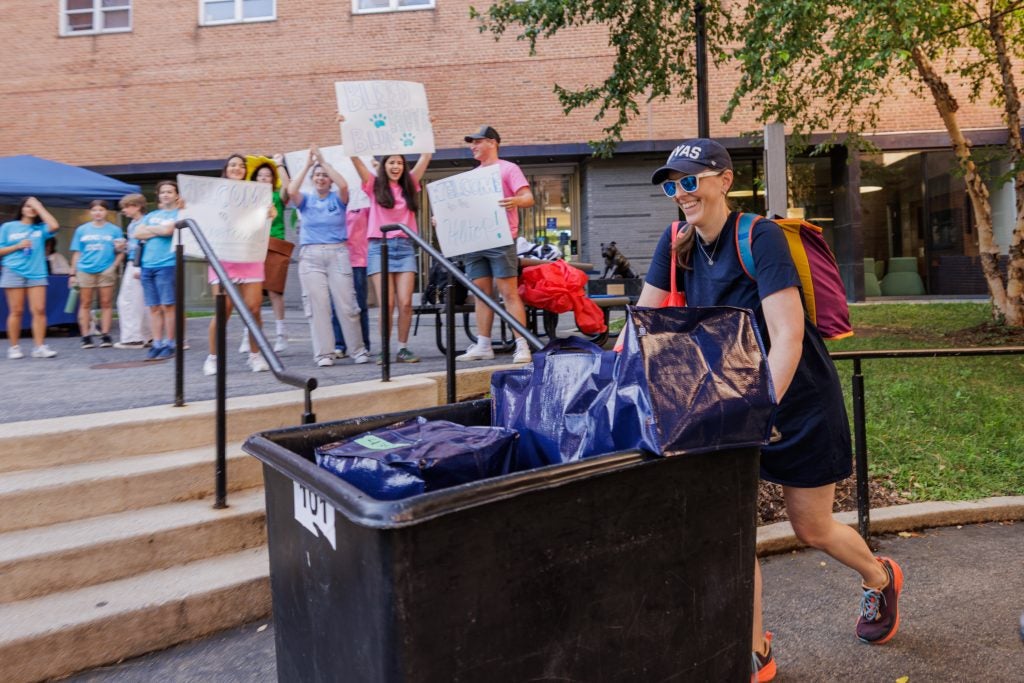Young man with a moving bin smiling as Hoyas cheer him on