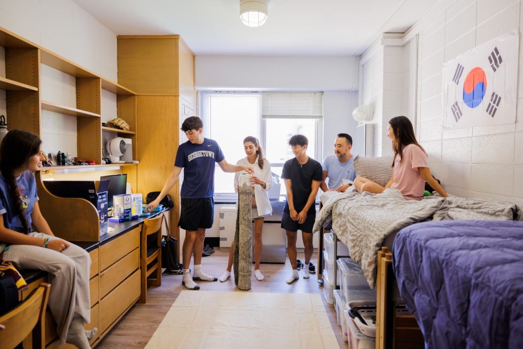 A family talking and moving into a brightly lit dorm room