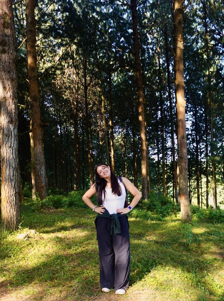 Young woman with hands on hips and smiling outside