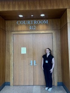 A student poses in front of the entryway to a courtroom