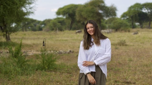Young woman smiling while standing outside in a safari
