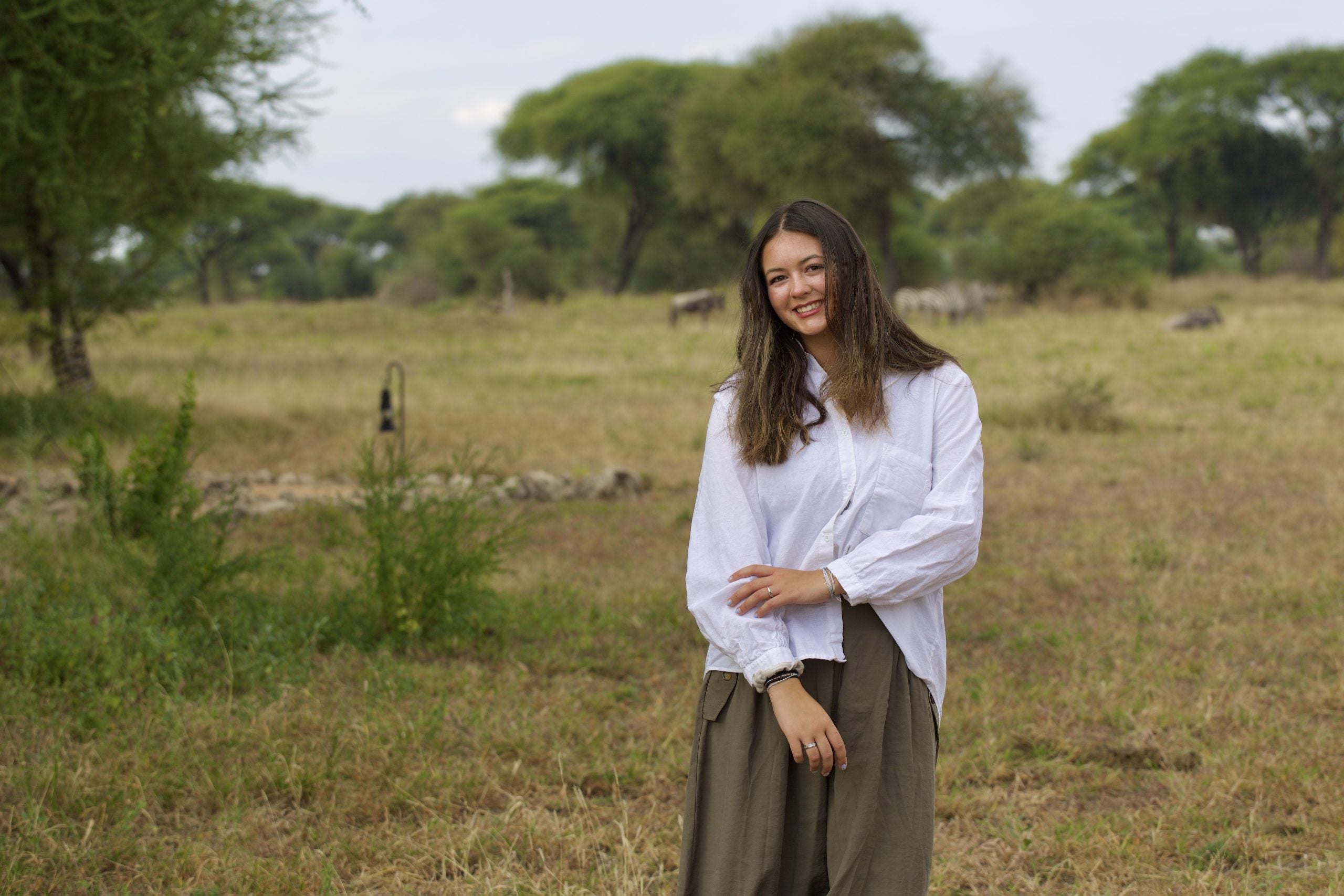 Young woman smiling while standing outside in a safari