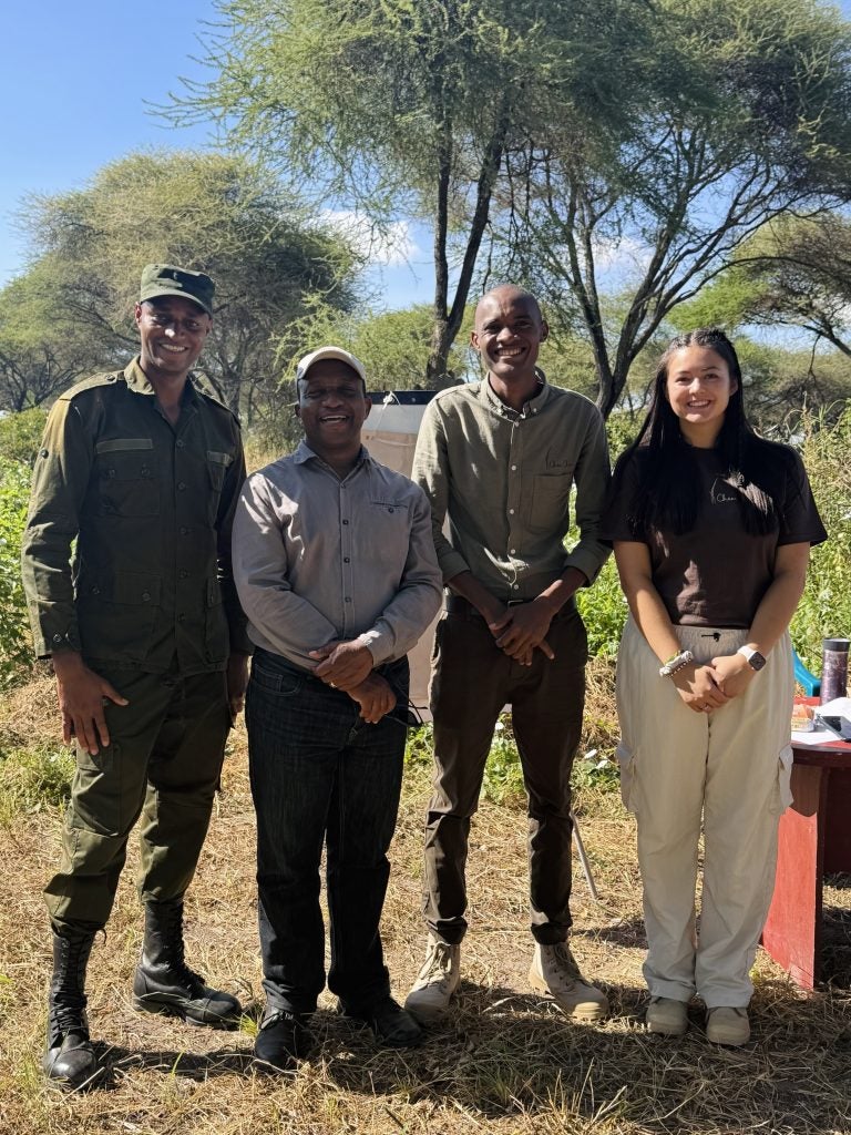 Young woman with three men outside at a safari
