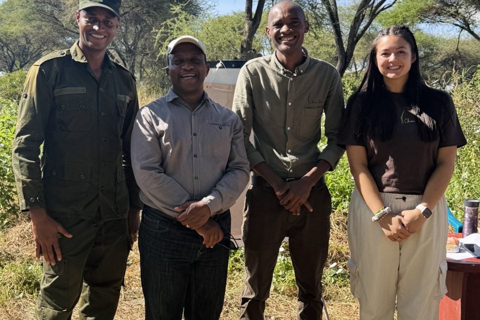 Young woman with three men outside at a safari