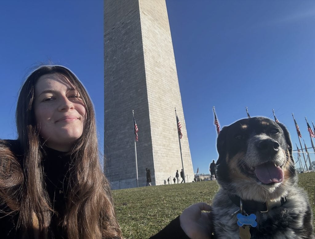 Young woman with a dog on a sunny day in front of Washington Monument