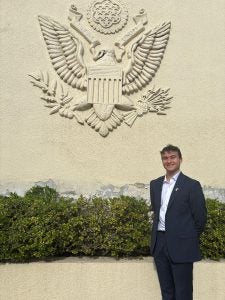 A student stands outside an emblem of the American embassy in Santiago, Chile