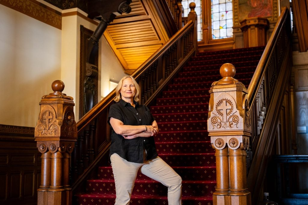 A woman poses on a staircase inside Healy Hall