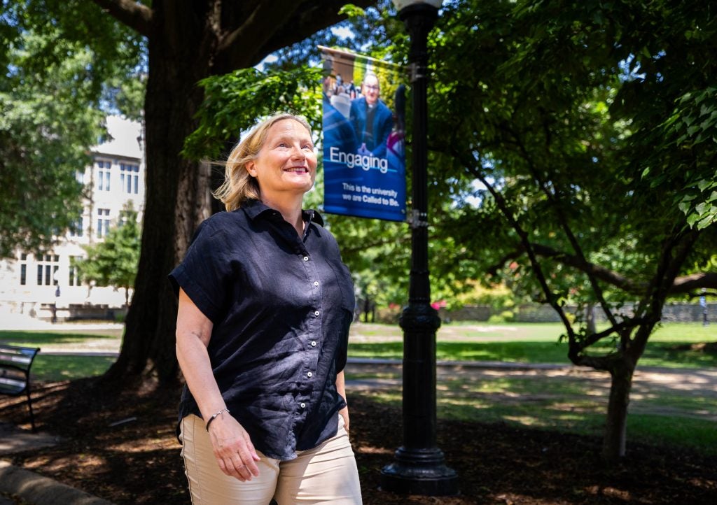 A woman looks up and smiles while walking on Georgetown's campus on a sunny day