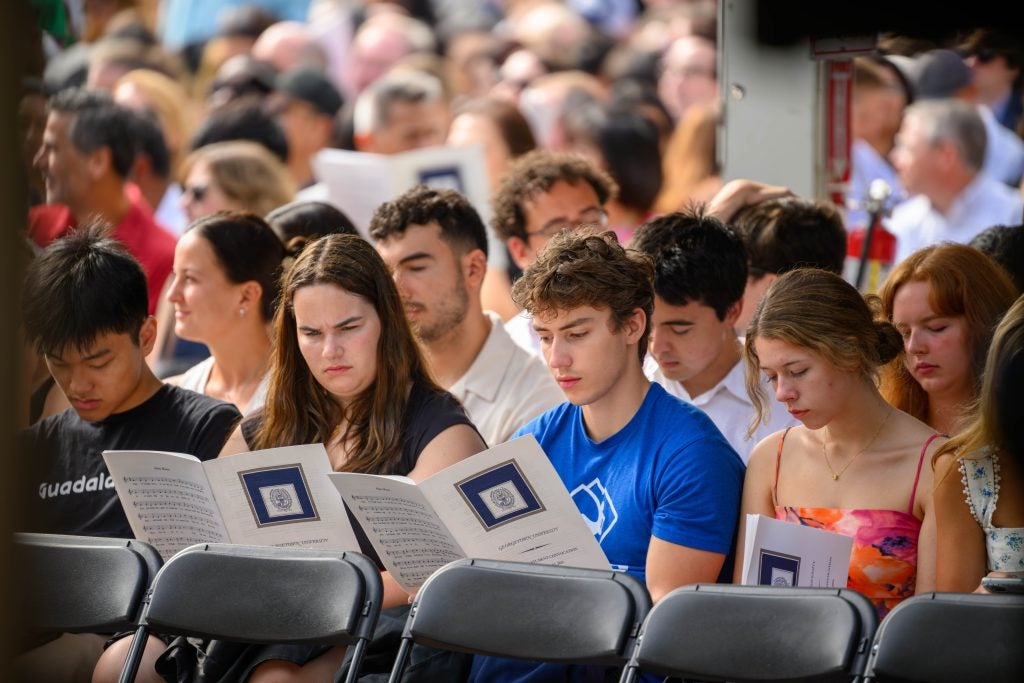 Students look at a program while seated