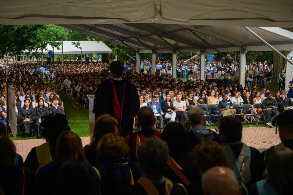 A Black woman speaks at a podium facing a large crowd on Copley Lawn