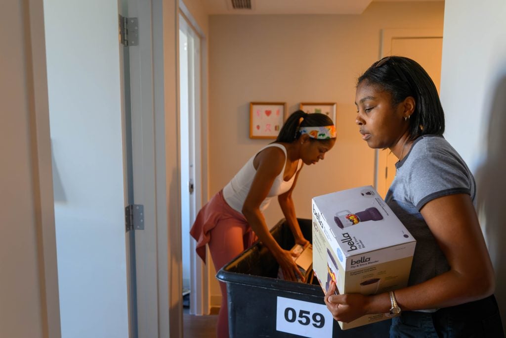 Two young Black women unloading a moving bin