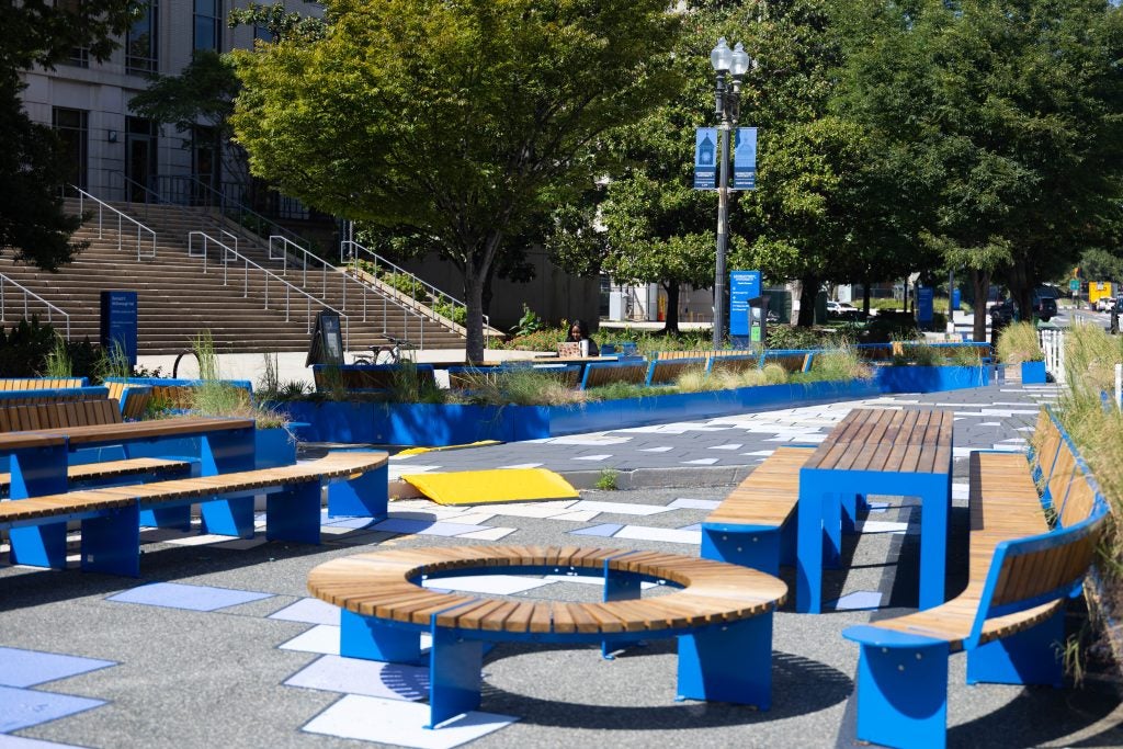 Bright blue outdoor seating on a plaza outside a school building