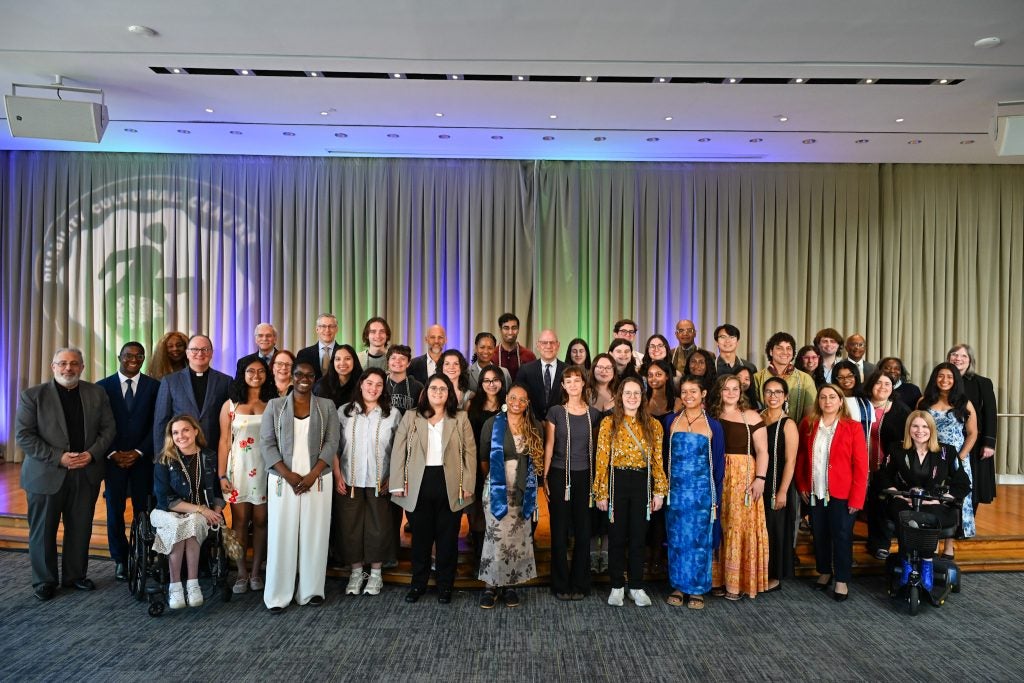 Group photo of several dozen people at a graduation celebration indoors