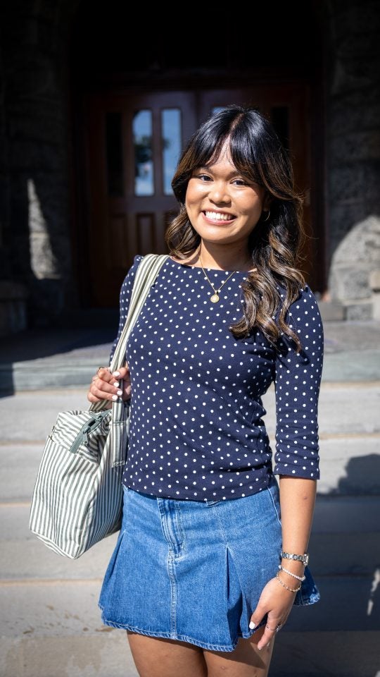 Young Asian woman in blue shirt with handbag smiling while on Healy steps