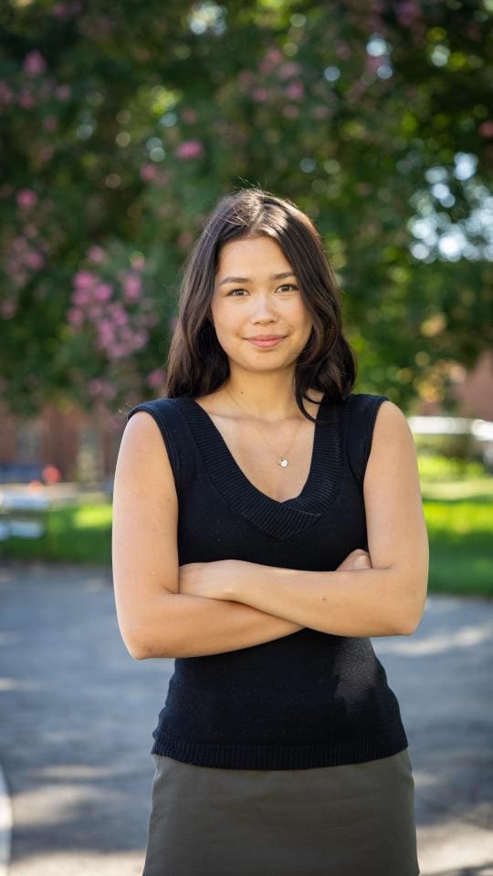 Young Asian woman with arms crossed and smiling outside