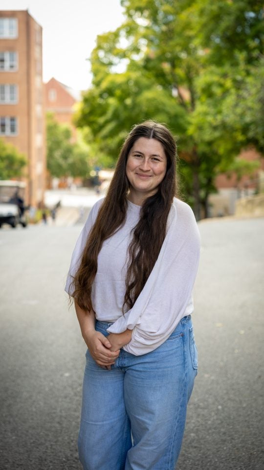 Young Caucasian woman in white shirt smiling while outside on a road