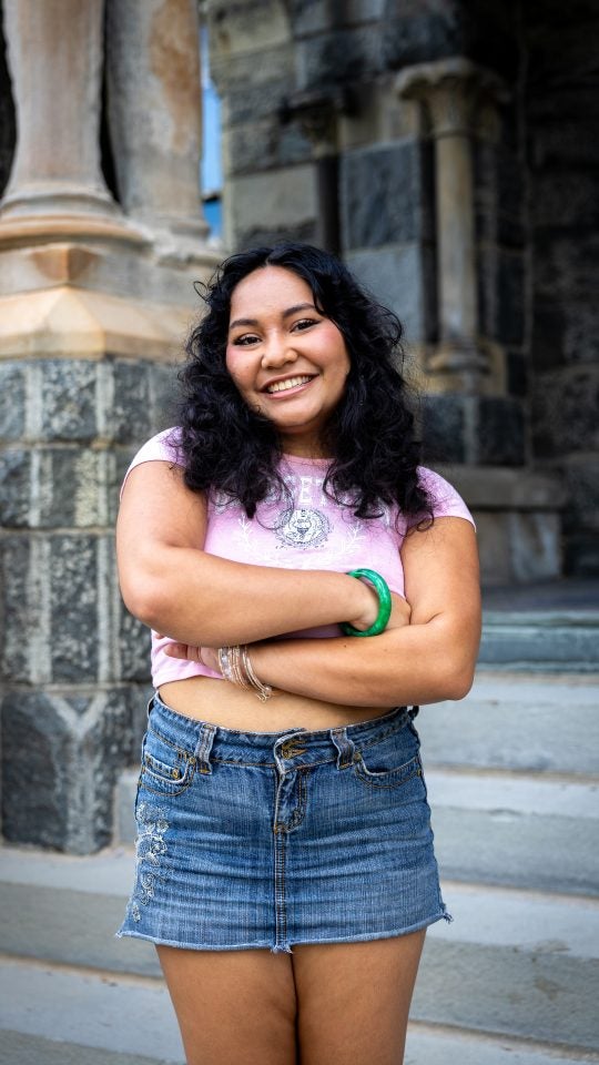 Young woman in a pink shirt smiling with arms crossed