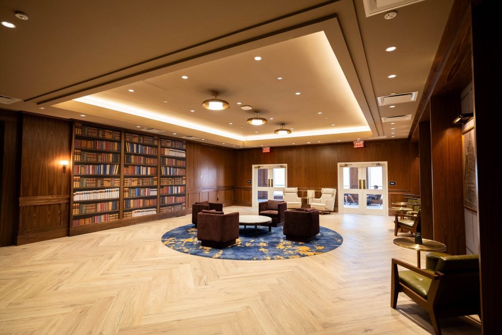 A hotel lobby with sleek and shiny wooden walls and bookshelves
